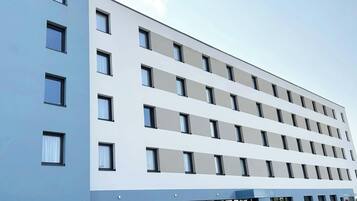 A multi-story hotel with a modern facade, featuring a series of windows and a flat roof.