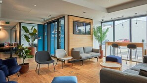 A modern lobby with seating areas, a reception desk, and large windows. - B&B Hotel Deauville-touques (Touques)