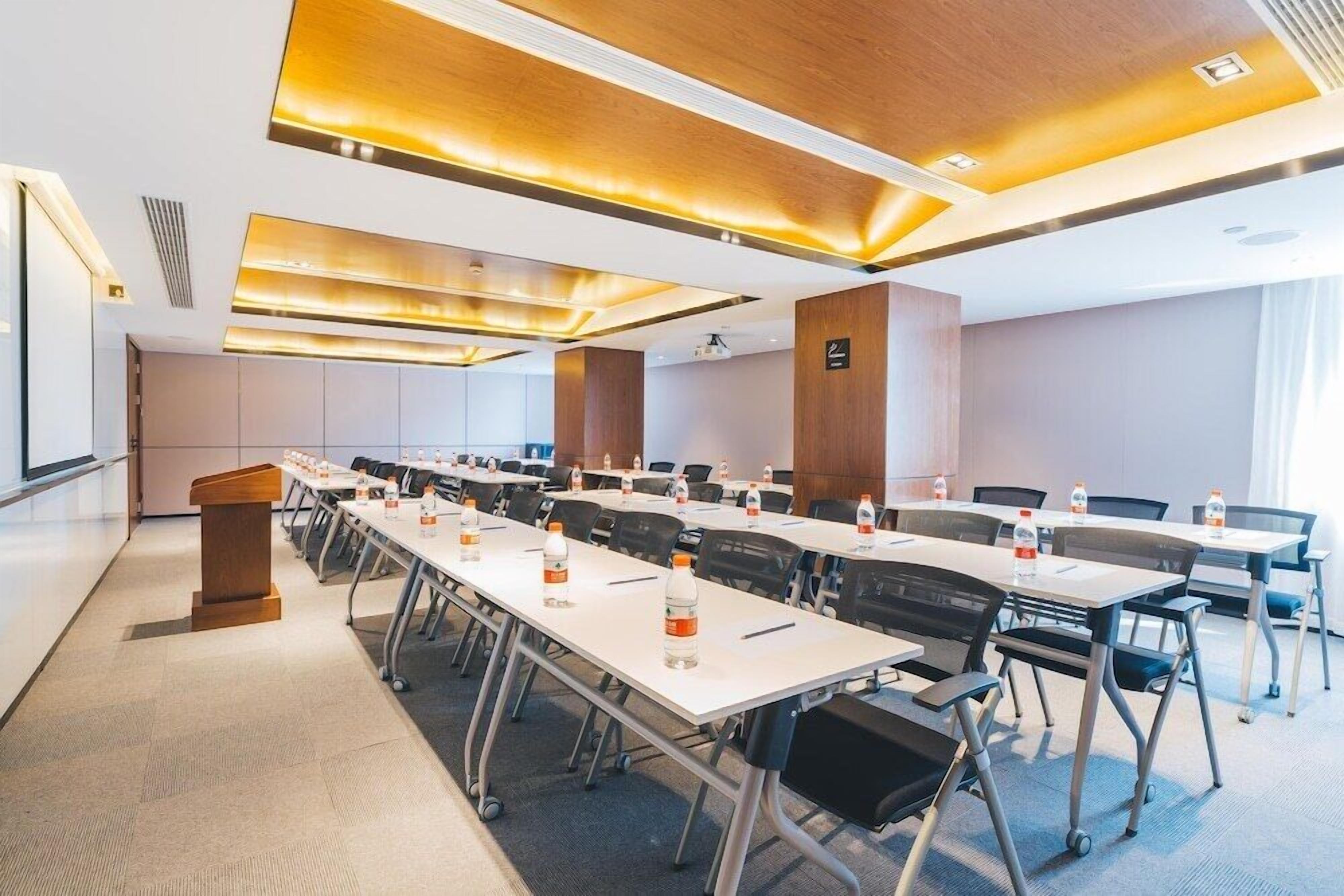 A conference room with white tables, black chairs, and a podium.