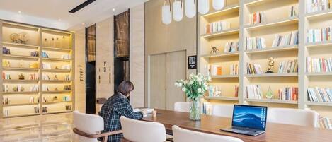 A modern library with bookshelves, a wooden table, and chairs.
