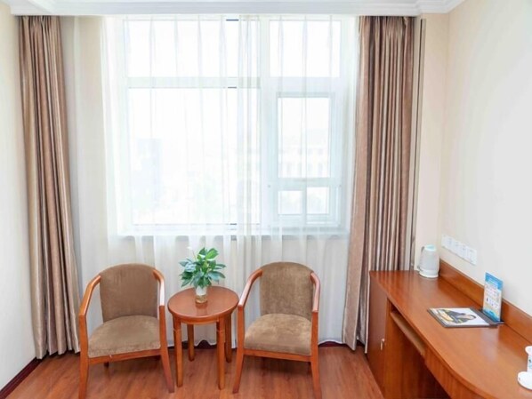 A room with two wooden chairs, a small round table, and a potted plant. - Greentree Inn Tangshan Ring Road South Ring and Fuxing Road Express Hotel (Tangshan)