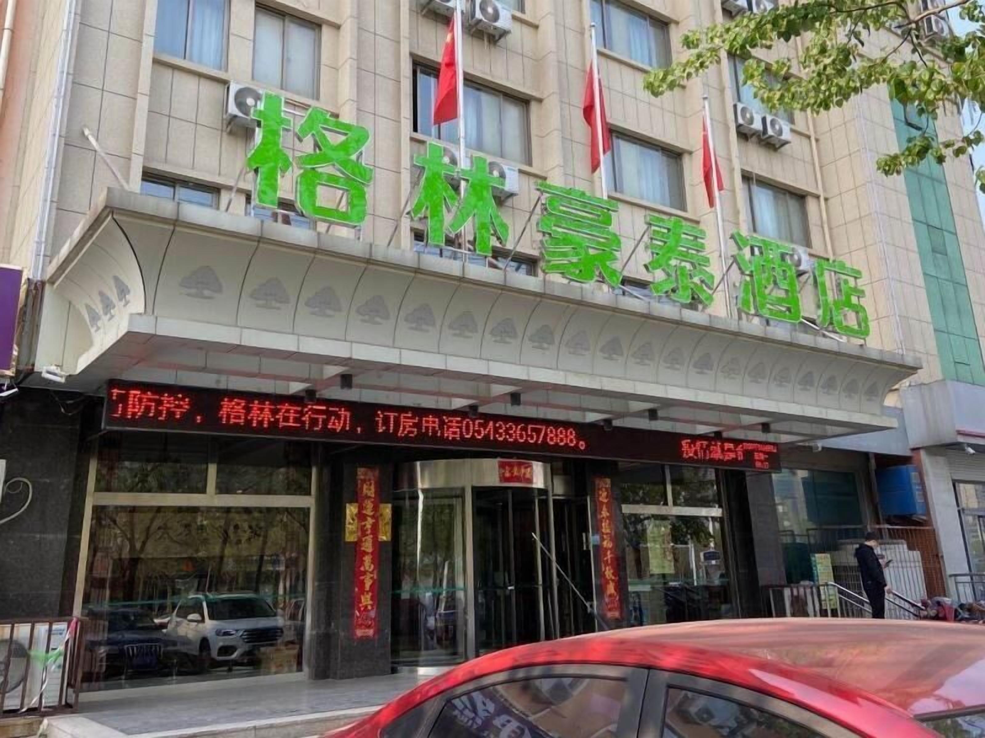 A hotel with a green signboard and red flags.