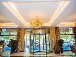 Vestíbulo de hotel con puerta giratoria, ventanas amplias y un candelabro.