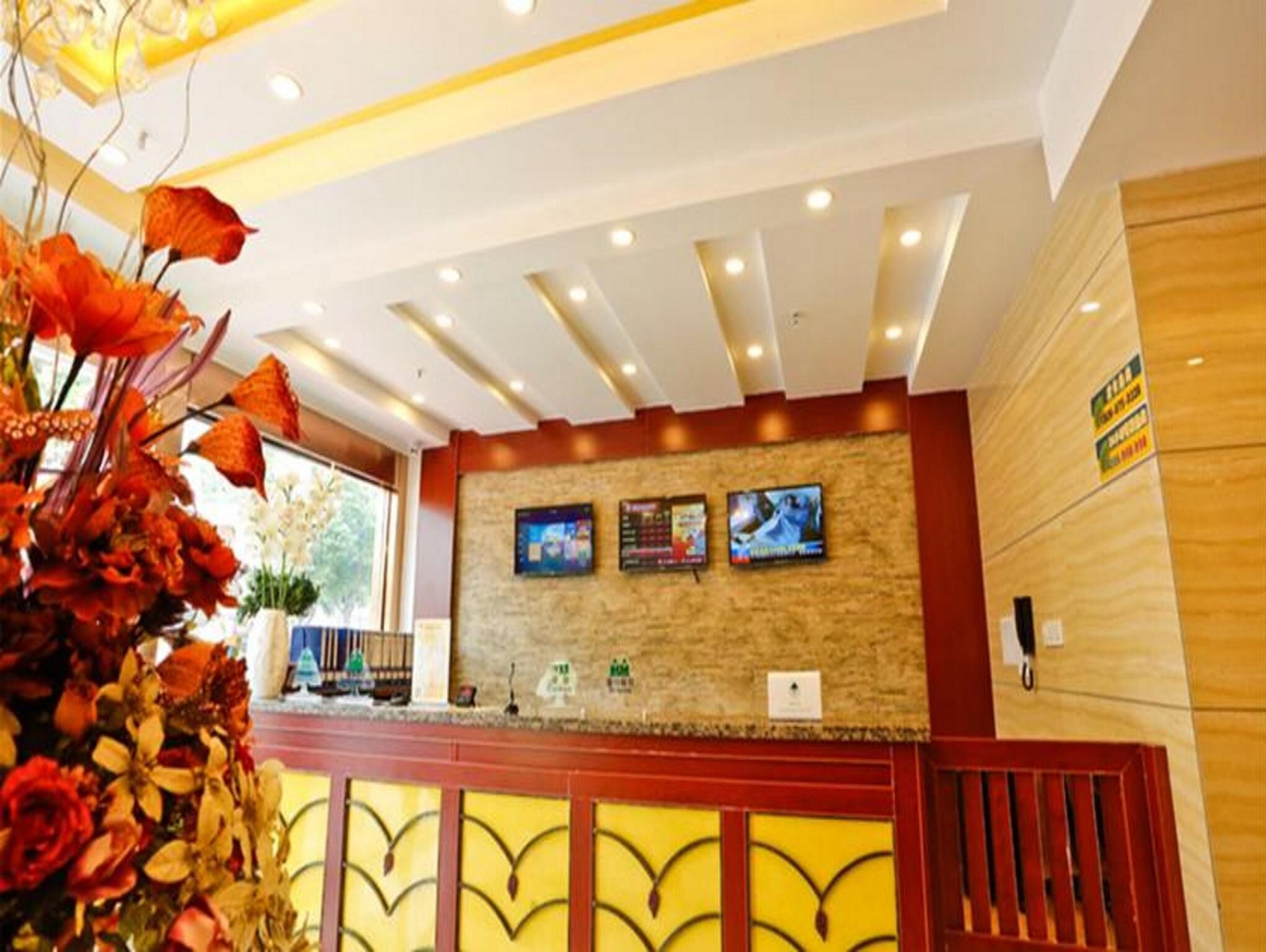 A reception area with a wooden counter, two monitors, and a decorative flower arrangement.