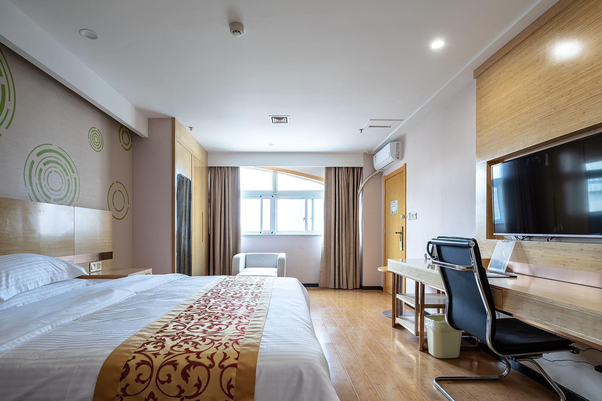 A hotel room with a bed, desk, chair, TV, and a window.