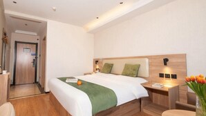 Una habitación de hotel con cama, mesita de noche, silla y una pequeña mesa con un jarrón de flores.