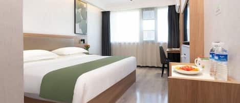 A hotel room with a bed, a desk with a chair, a window with curtains, and a water dispenser on the desk.