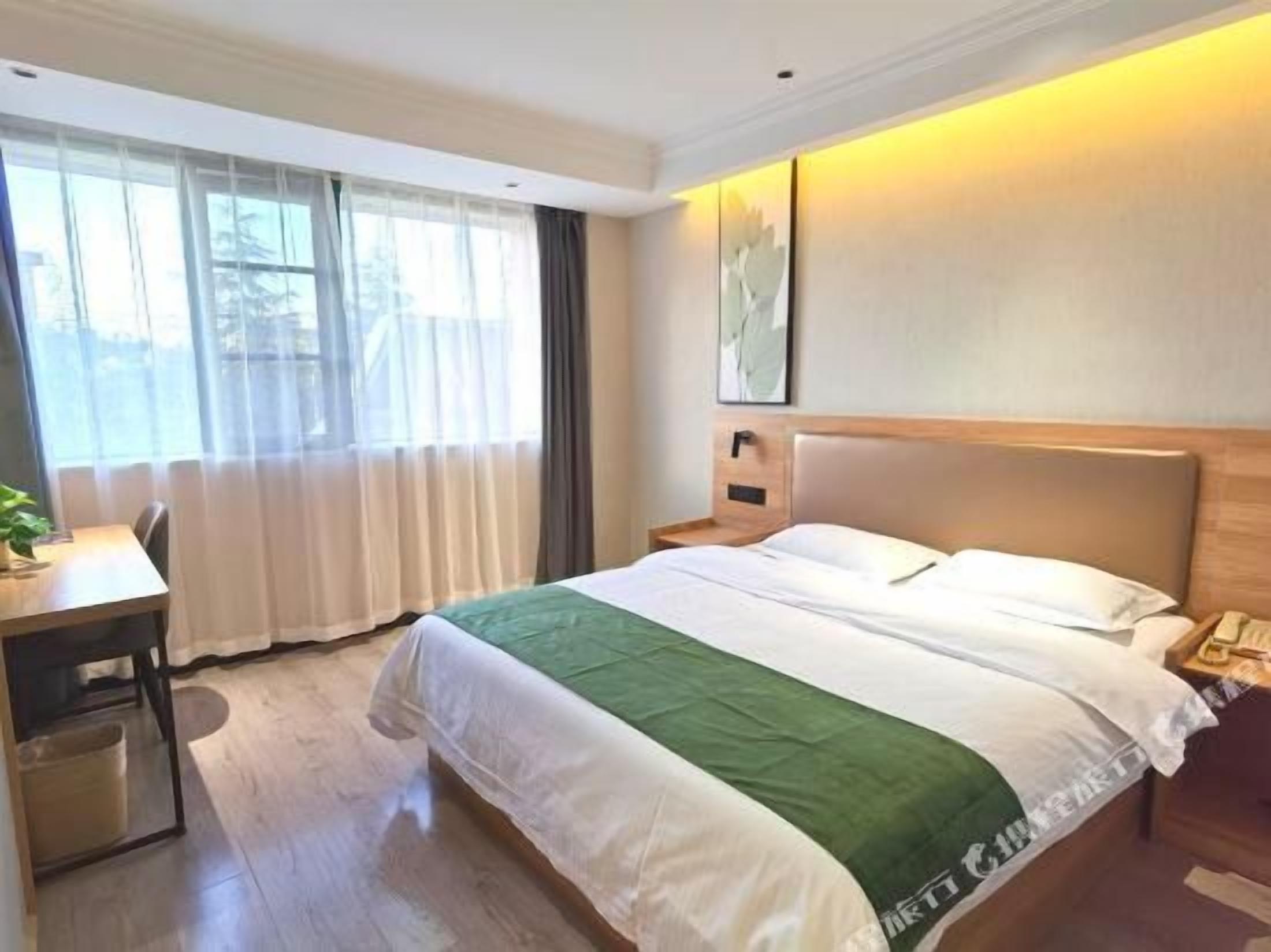 A hotel room with a bed, a desk, and a window.