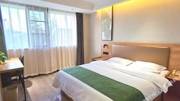 A hotel room with a bed, a desk, and a window.