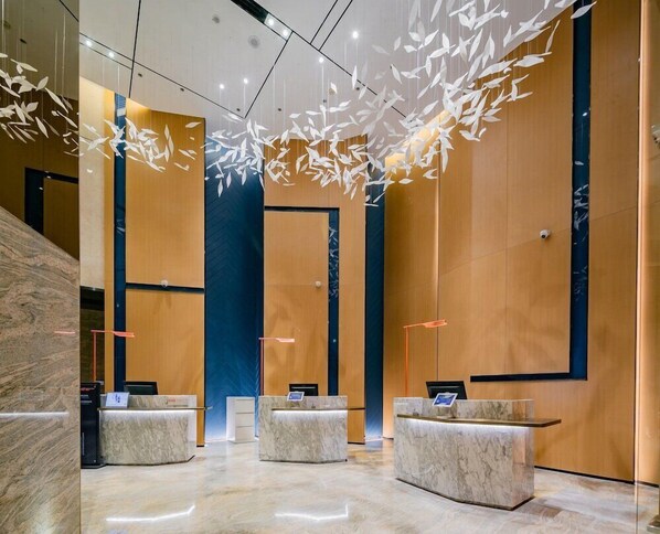 A modern lobby with marble reception desks, a central blue accent wall, and hanging leaf-like light fixtures. - Holiday Inn Express Xi an High Tech Zone North (Xi'an)