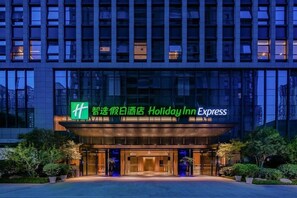 A Holiday Inn Express hotel entrance with a modern glass facade and illuminated signage. - Holiday Inn Express Xi an High Tech Zone North (Xi'an)
