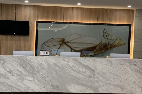 A reception desk with a large glass display case, a mounted television, and a marble countertop. - Greentree Inn Anhui Suzhou Yongqiao Qiongyun Market (Suzhou)