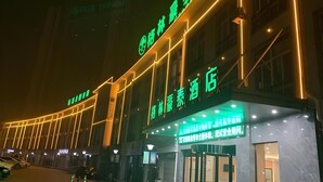 Ett hotell med en framträdande grön skylt och upplysta neonljus.