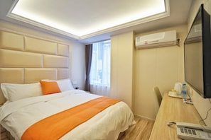 Habitación de hotel con una cama grande, un escritorio con teléfono y un equipo de aire acondicionado en la pared.