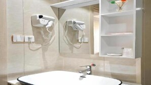 A bathroom with a white sink, two hair dryers mounted on the wall, and a shelf with toiletries. - Shell Shanghai Baoshan District Songbin Road Subway Station Hotel (Shanghai)