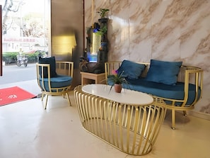 Un interior moderno con sofá, dos sillones, una mesa de centro y plantas decorativas.