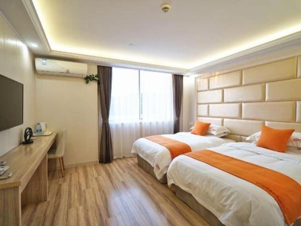 A hotel room with two beds, a desk, and a large window.