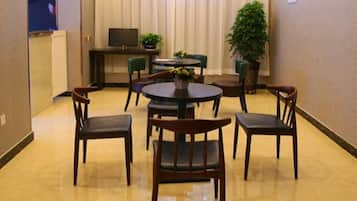 Un comedor con una mesa redonda, seis sillas, un televisor y plantas en macetas.