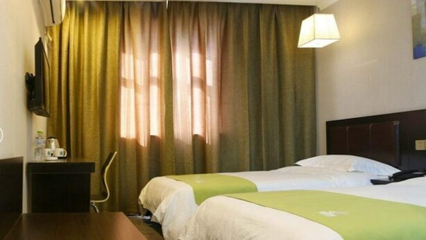 Ein Hotelzimmer mit zwei Betten, einem Schreibtisch, einem Stuhl und einer Lampe.