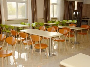 A dining area with multiple tables and chairs, large windows, and curtains. - Greentree Inn Lu an Jin an District Bus North Station Express Hotel (Lu'an)