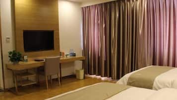 Una habitación de hotel con un escritorio de madera, un televisor, una cama y una cortina.