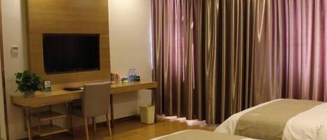 Una habitación de hotel con un escritorio de madera, un televisor, una cama y una cortina.