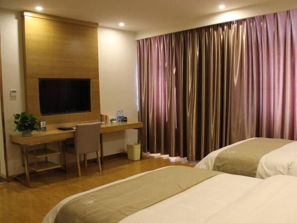 Een hotelkamer met een houten bureau, een televisie, een bed en een gordijn.
