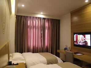 Une chambre d’hôtel avec un lit, un bureau avec un ordinateur, une télévision et un rideau.