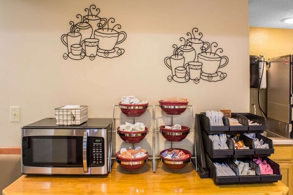 A kitchenette with a microwave, a coffee station with cups and saucers, and a buffet area with bowls of food. - Econo Lodge Sioux Center (Sioux Center)