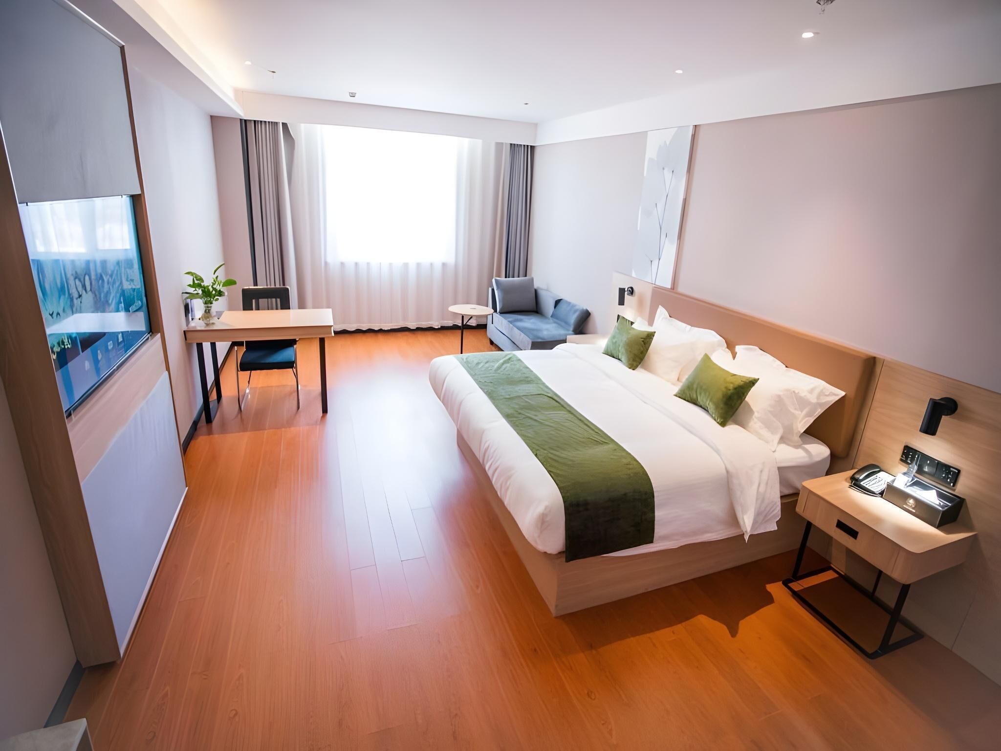 A modern hotel room with a large bed, a desk, a chair, and a small table.
