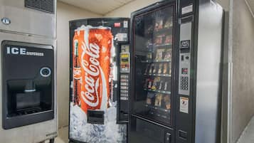 A vending machine with a Coca-Cola logo, an ice dispenser, and a selection of snacks.
