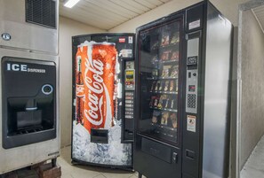 Máquina expendedora con logotipo de Coca-Cola, dispensador de hielo y variedad de refrigerios.