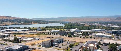 An aerial view of a commercial area with industrial buildings, a parking lot, and a body of water in the background.