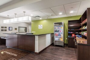 Un espace d’accueil avec un comptoir, un réfrigérateur rempli de boissons et un distributeur automatique.
