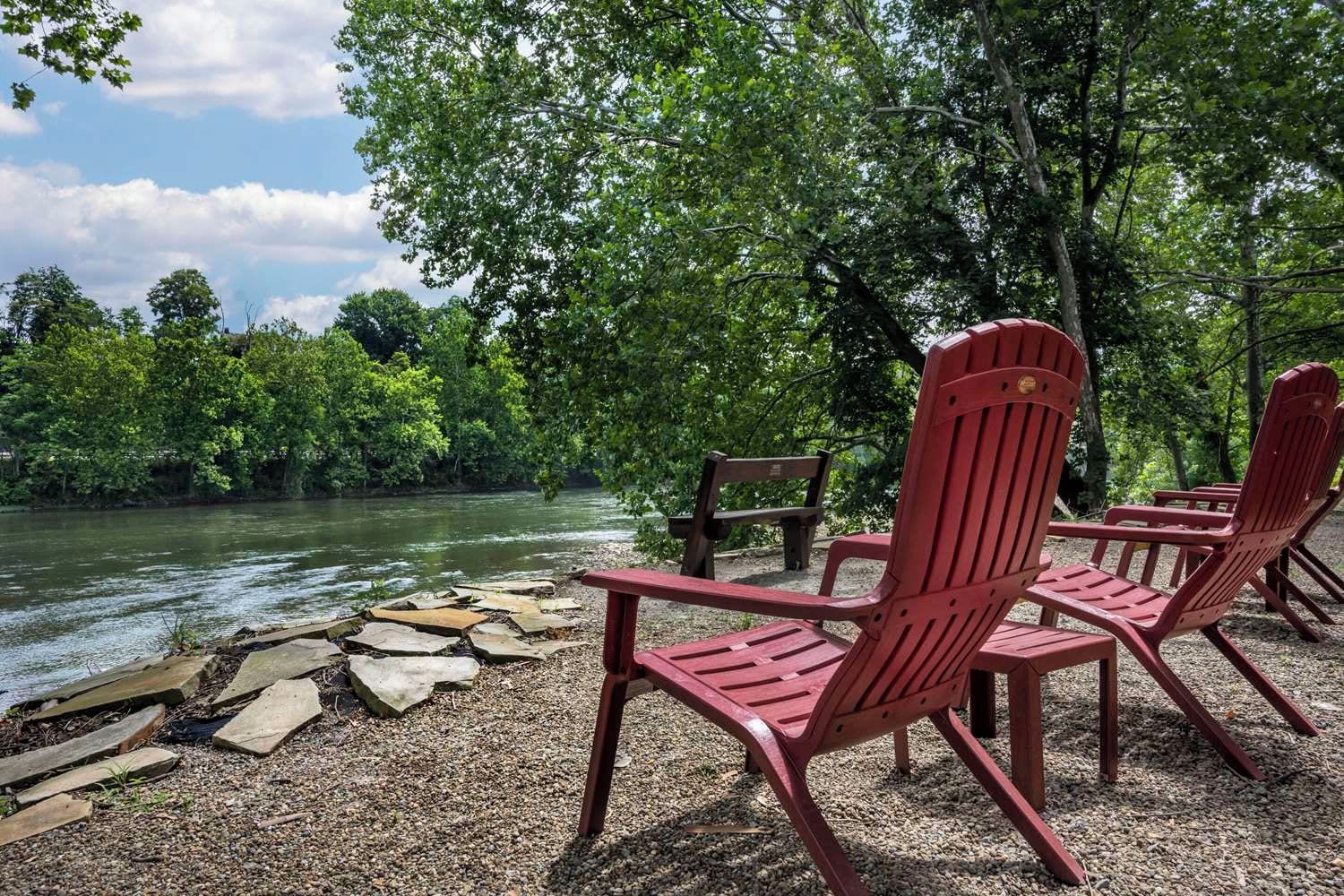 A riverside seating area with Adirondack chairs and a wooden deck.