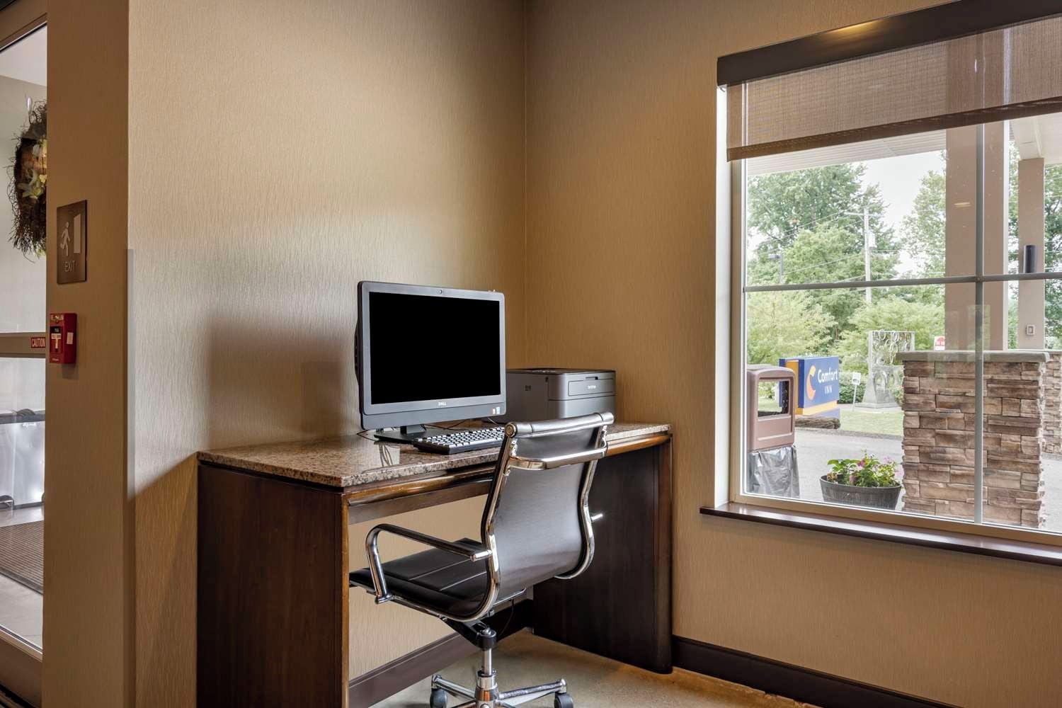 A hotel room with a desk, computer, and chair.