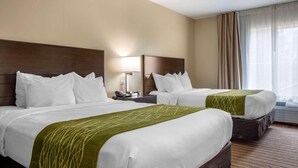 A hotel room with two beds, a nightstand with a lamp, a window with curtains, and a carpeted floor. - Comfort Inn Connellsville Riverview (Connellsville)