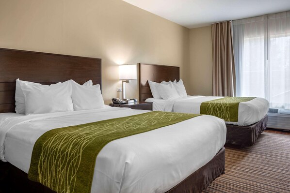 A hotel room with two beds, a nightstand with a lamp, a window with curtains, and a carpeted floor. - Comfort Inn Connellsville Riverview (Connellsville)