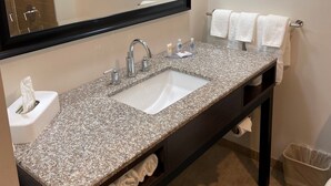 A bathroom with a granite countertop, a white sink, a mirror, and a towel rack. - Comfort Inn Connellsville Riverview (Connellsville)