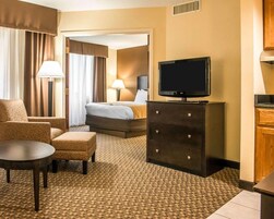 A hotel room with a bed, a TV, a desk, a chair, and a dresser.