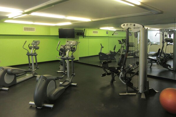 A gym with various exercise machines, a large mirror, and a television on the wall. - Pittsburgh PA (Pittsburgh)