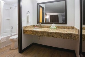 A bathroom with a granite countertop, a sink, a mirror, a towel rack, and a shower area. - Econo Lodge Lithonia (Lithonia)