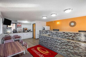 A hotel lobby with a reception desk, a clock, a microwave, and a dining area with tables and chairs. - Econo Lodge Lithonia (Lithonia)