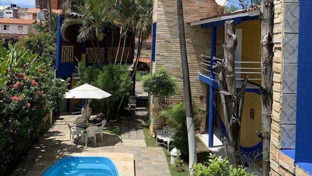 Un espace piscine agrémenté d’un palmier, de mobilier d’extérieur et d’un bâtiment aux touches de couleur bleue.