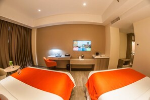 A hotel room with two beds, a desk, a TV, and a small table with a plant.