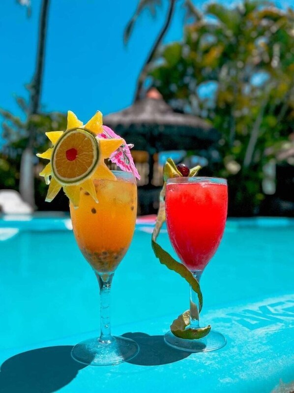 Two cocktails on a poolside table with a clear blue pool and tropical background. - Pousada Perola do Porto (Ipojuca)