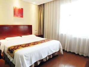 A hotel room with a large bed, a wooden headboard, a red abstract painting on the wall, and a window with curtains. - Greentree INN Beijing Fengtai Yungang Road Express (Beijing)