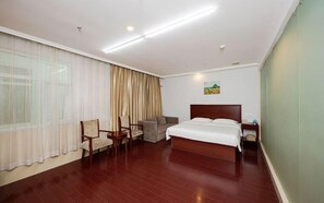 A hotel room with a large bed, a chair, a sofa, a nightstand, and a window with curtains. - Greentree Inn Beijing Chaoyang District Xizhihe Commercial Center Express Hotel (Beijing)