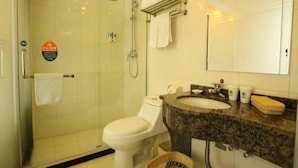 Une salle de bain avec une douche à parois de verre, des toilettes blanches, un lavabo en granit et un miroir au-dessus du lavabo.