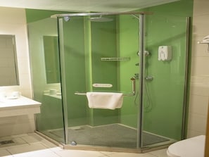 A glass-enclosed shower stall with a towel hanging on the door handle, a hand dryer, and a small shelf. - Greentree Inn Qingdao Jiaozhou Jiaoping Road Aviation Industry Park Express Hotel (Qingdao)